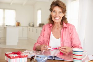 Senior woman scrapbooking at home smiling to camera